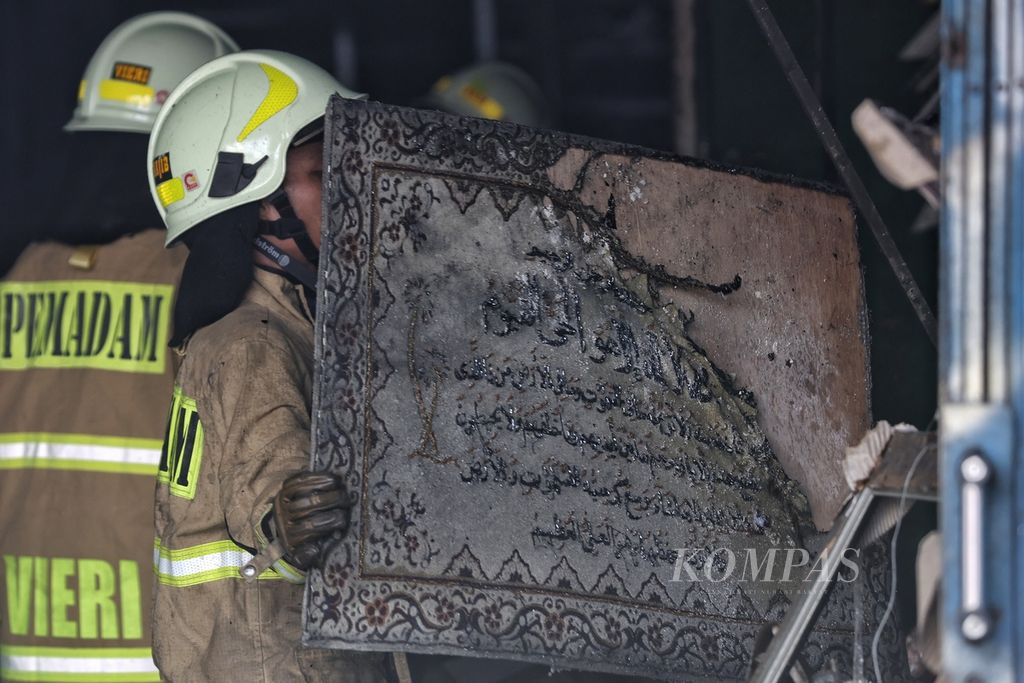 Petugas pemadam kebakaran mengambil kaligrafi sisa kebakaran di Jalan Mampang Prapatan, Jakarta, Jumat (19/4/2024). 