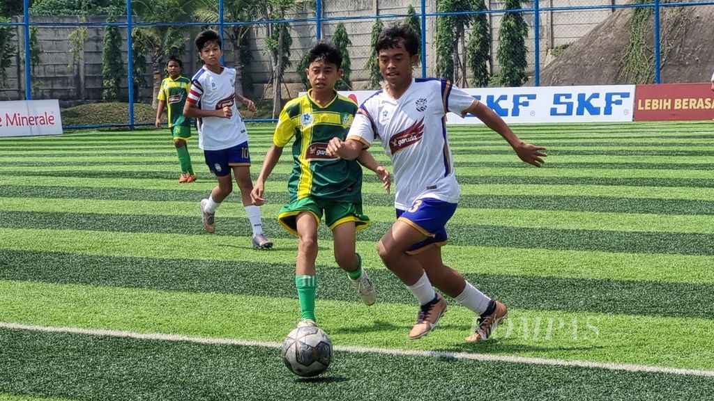Duel pemain Babek Soccer School (kanan) dengan pemain Siaga Pratama untuk memperebutkan bola pada laga pekan keempat Liga Kompas Kacang Garuda U-14, Minggu (17/12/2023), di Lapangan Dewantara, Tangerang Selatan, Banten. Babek SS menang, 1-0.