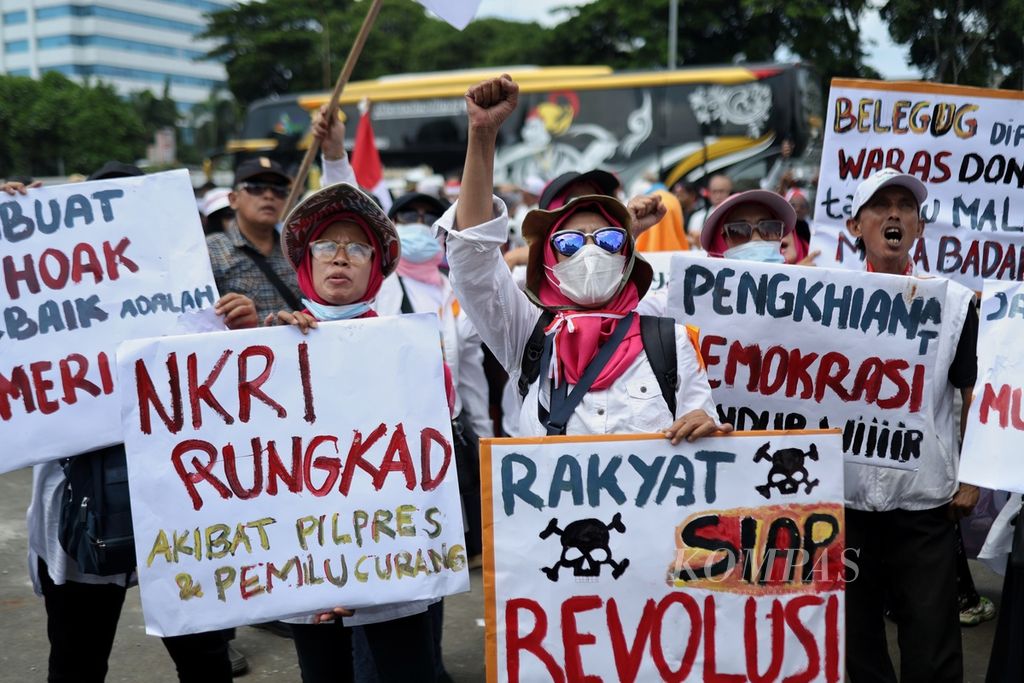 Para demonstran membawa poster berisi tuntutan penolakan pemilihan umum curang di depan Kompleks Parlemen, Senayan, Jakarta, Jumat (1/3/2024).