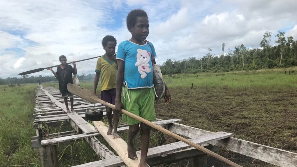 Anak-anak dari Kampung Somnak, Distrik Joutu, Kabupaten Asmat, Papua, menyusuri jalan-jalan di atas papan untuk menuju perkampungan, Rabu (14/8/2019).
