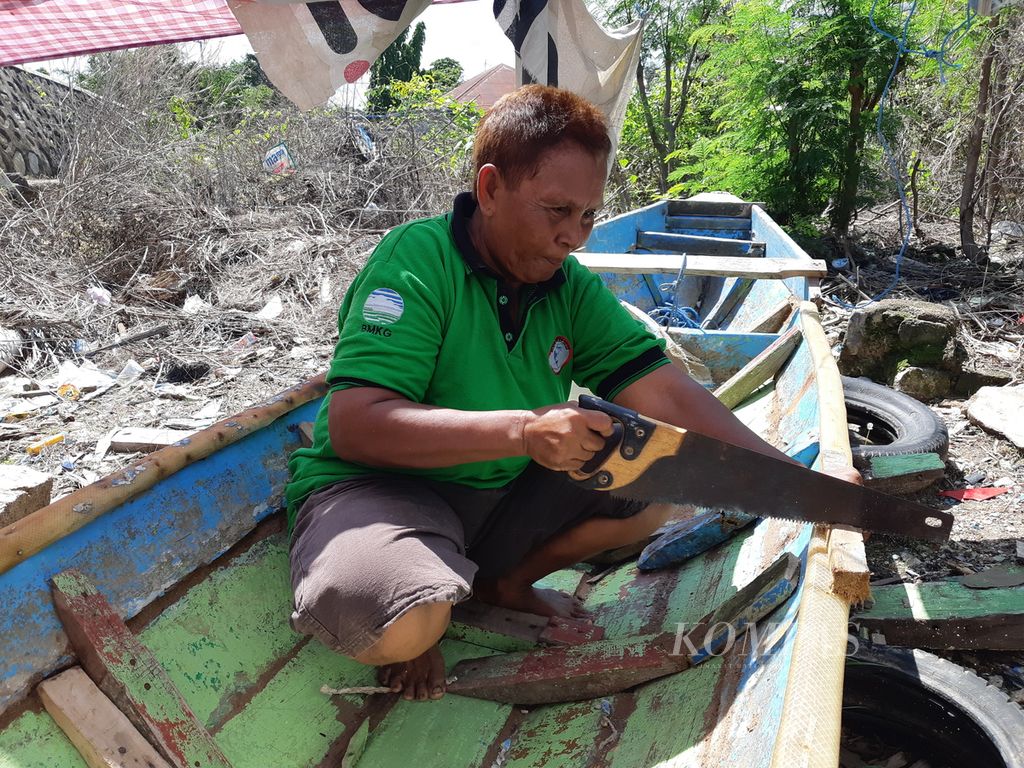 Mariam Badaruddin (59), nelayan perempuan, memperbaiki perahunya di Kelurahan Air Mata, Kota Kupang, Nusa Tenggara Timur, Selasa (15/11/2022). Perahu itu tanpa mesin sehingga digerakkan dengan cara didayung.