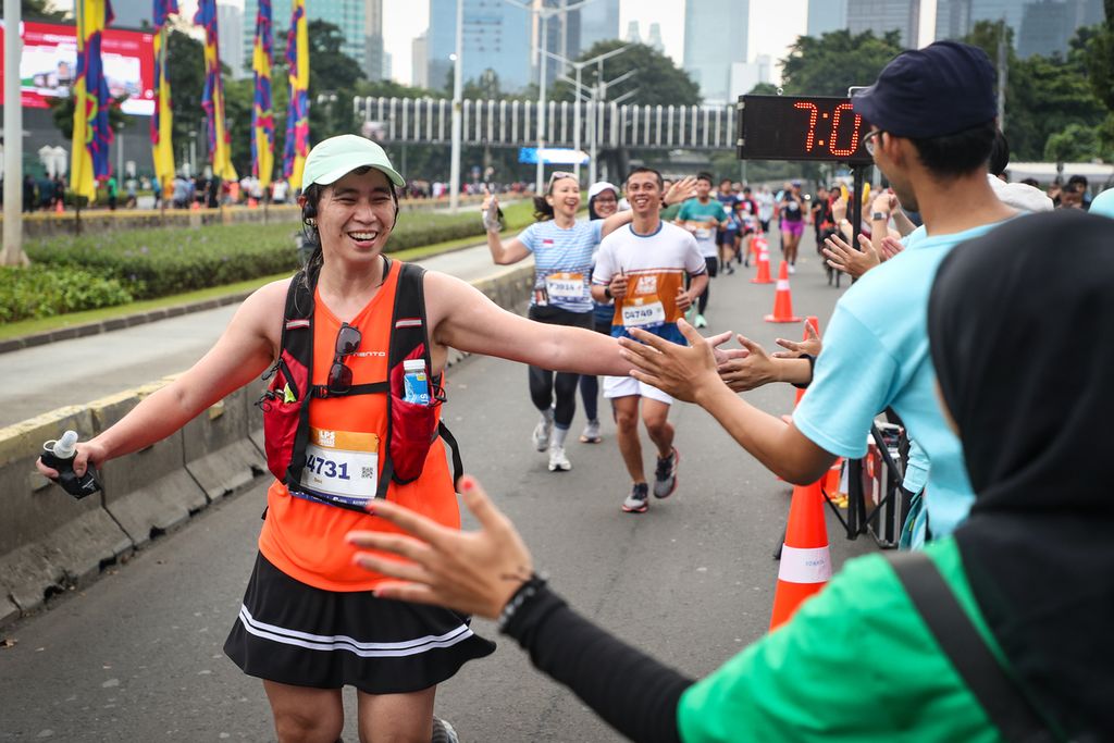 Panitia menyemangati peserta LPS Monas Half Marathon yang melintas di Jalan Jenderal Sudirman, Jakarta, Minggu (2/7/2023). 