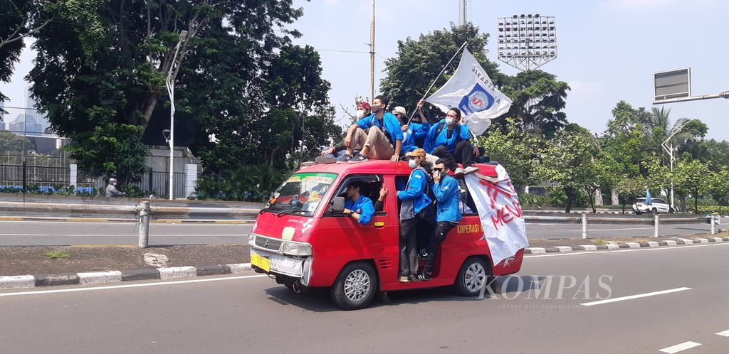 Sekelompok mahasiswa peserta unjuk rasa di DPR/MPR melintas dengan angkot sewaan di Jalan Gerbang Pemuda, Jakarta Pusat, Senin (11/4/2022).