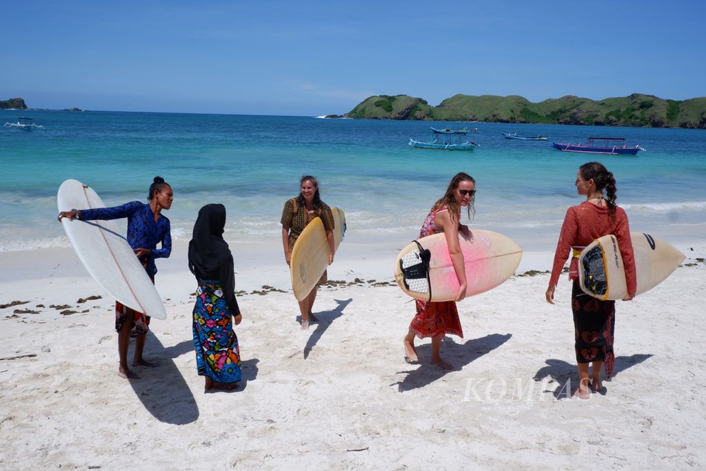 Para peselancar (<i>surfer</i>) perempuan membawa papan <i>surfing</i> masing-masing yang mereka gunakan saat peringatan Hari Kartini di perairan Pantai Tanjung Aan, Kawasan Ekonomi Khusus Mandalika, Pujut, Lombok Tengah, Nusa Tenggara Barat, Kamis (21/4/2022). Dalam kegiatan yang diselenggarakan komunitas Lombok Surfer Girls, para peselancar menaklukkan ombak Pantai Aan dengan mengenakan kebaya dan kain batik. 
