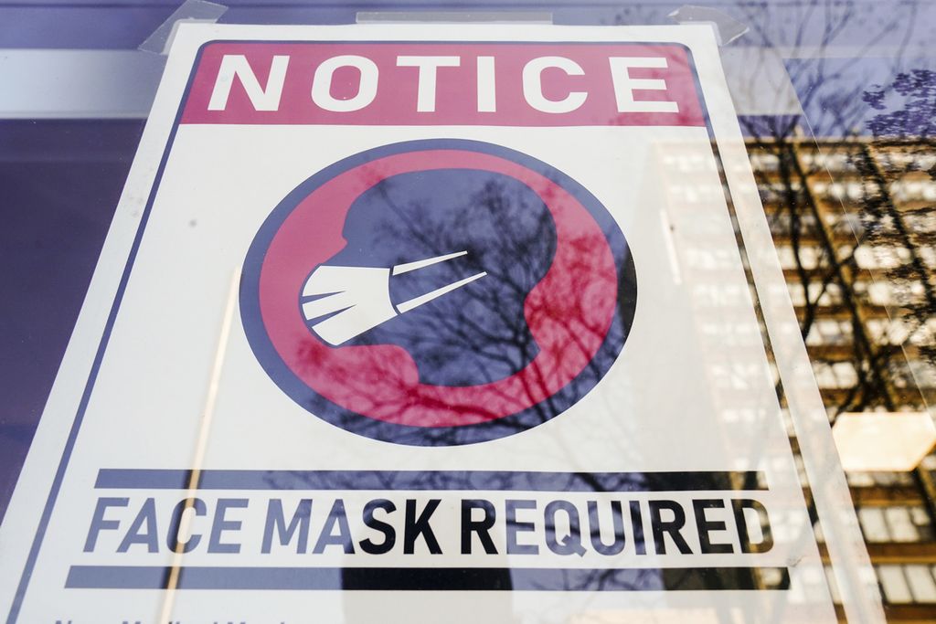 Poster yang mewajibkan pengunjung bermasker terpampang di jendela sebuah toko di Philadelphia, Negara Bagian Pennsylvania, Amerika Serikat, pada 16 Februari 2022. 