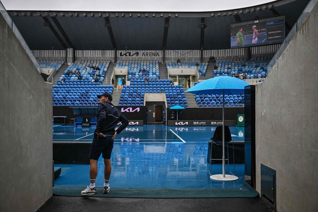 Anggota tim mengecek kondisi lapangan yang diguyur hujan pada hari ketiga turnamen tenis Grand Slam Australia Terbuka di Melbourne Park, Rabu (18/1/2023).