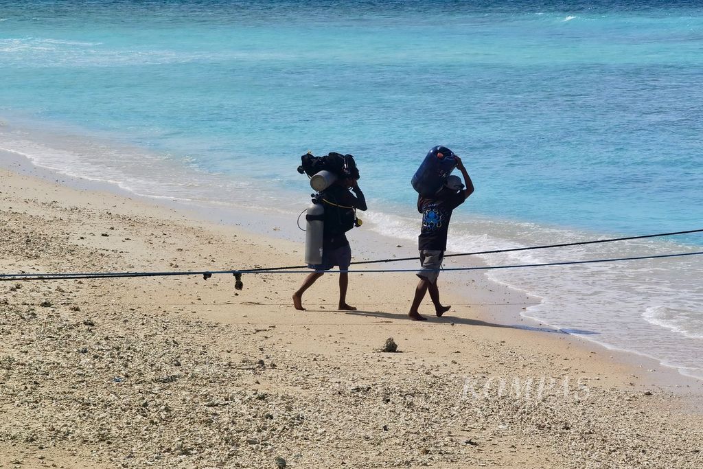 Pemandu selam membawa peralatan menyelam menuju kapal di Gili Meno di Desa Gili Indah, Kecamatan Pemenang, Kabupaten Lombok Utara, Nusa Tenggara Barat, Kamis (13/7/2023).