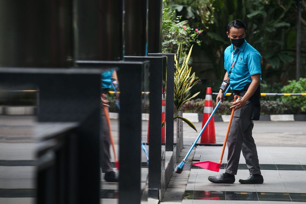 Pekerja alih daya membersihkan sebuah gedung perkantoran di kawasan Kuningan, Jakarta, Rabu (23/2/2022). Pemerintah masih mengkaji substansi revisi peraturan baru terkait pencairan Jaminan Hari Tua yang belakangan memancing penolakan kuat dari publik. 