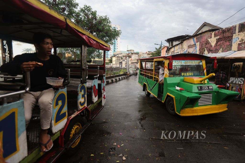 Students ride on odong-odong on Inspeksi Kampung Pulo Street, Jakarta, on Monday (4/3/2024). Odong-odong has become one of the residents' choices as a cheap recreational vehicle. The vehicle also serves as an alternative transportation when public transportation does not reach their area. However, odong-odong has been banned from operating on the streets since 2019 and is often involved in accidents.