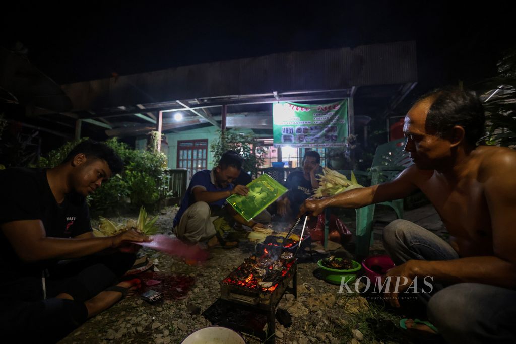 Warga membakar jagung dan ikan untuk merayakan tahun baru di Desa Sukaraja, Kecamatan Sepaku, Kabupaten Penajam Paser Utara, Kalimantan Timur, Minggu (31/12/2023). 