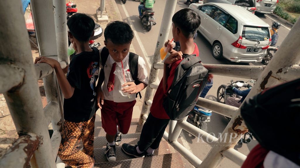 Pelajar sedang minum dengan sedotan dari kemasan kantong plastik di Jalan Basuki Rachmat, Jakarta Timur, Selasa (17/5/2022).