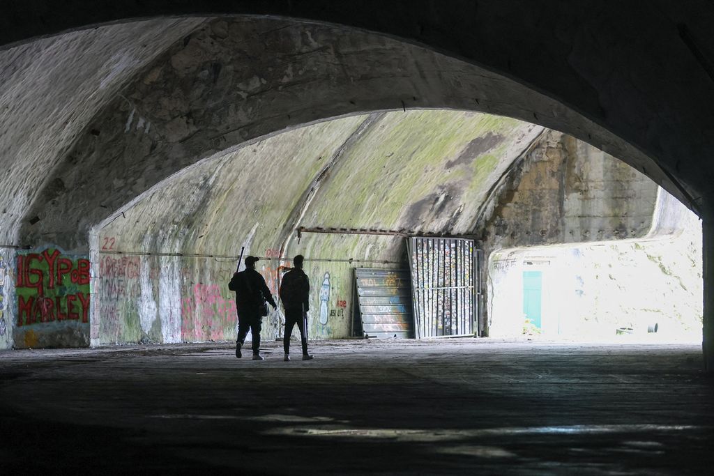 Pengunjung Angelo Virag (kiri) dan Mario Garbin (kanan) berjalan di pintu masuk pangkalan udara militer bawah tanah.