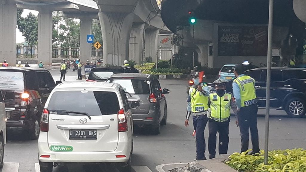 Beberapa polisi berjaga di perempatan menuju Jalan Gatot Subroto yang baru menerapkan aturan ganjil genap, Senin (25/10/2021) sore.
