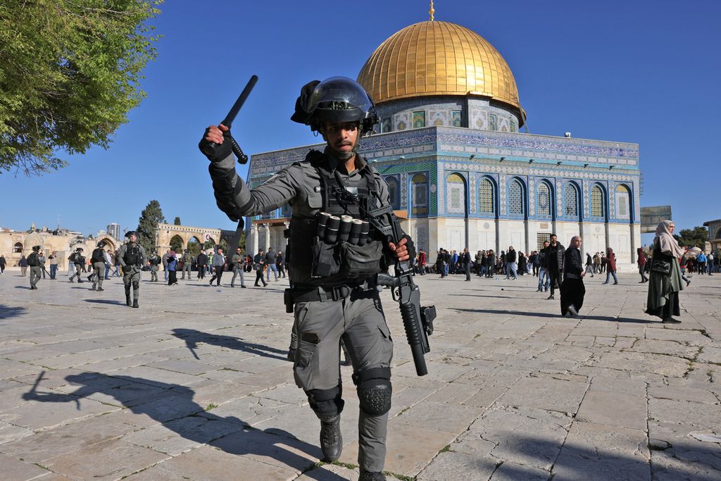 Anggota pasukan keamanan Israel mengangkat tongkat di depan bangunan masjid Kubah Batu (Dome of the Rock) dalam bentrokan di kompleks Masjidil Aqsa, Jerusalem, 15 April 2022. 