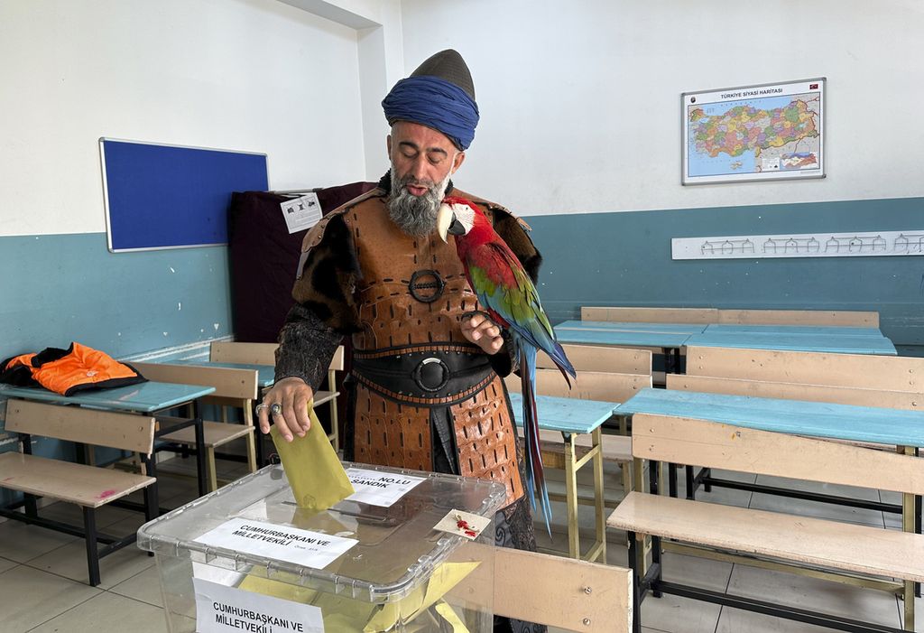 Nazim Cihan memegang burungnya saat memberikan suara dalam pemilu di sebuah tempat pemungutan suara di Istanbul, Turki, Minggu (14/5/2023). 