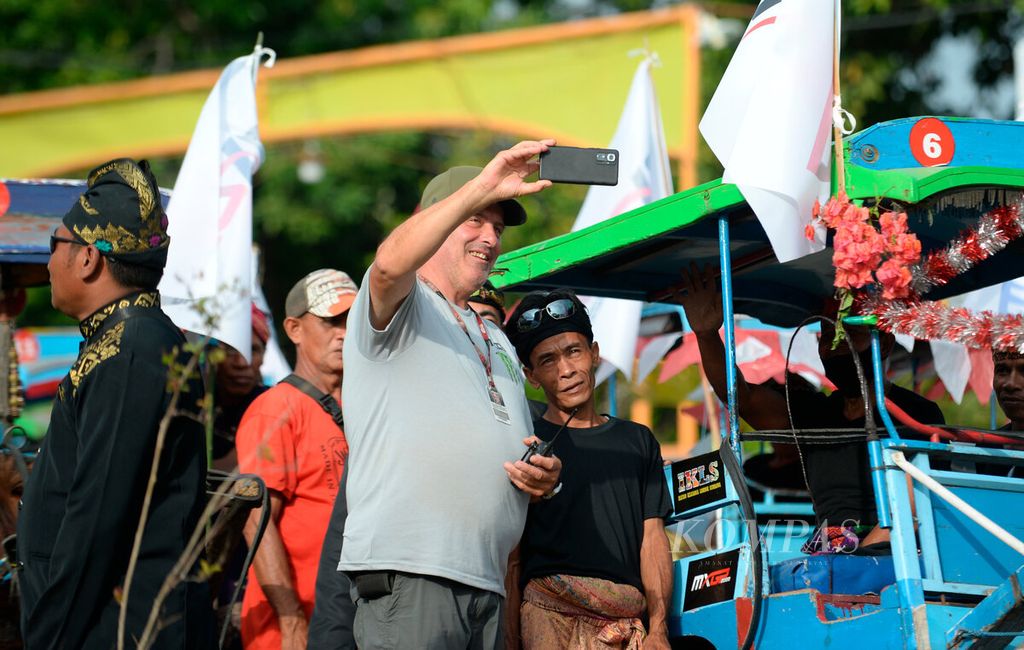 Salah satu anggota rombongan tim Motorcross Grand Prix (MXGP) berfoto dengan warga saat acara penyambutan di Kantor Bupati Sumbawa, Kabupaten Sumbawa, Provinsi Nusa Tenggara Barat, Jumat (24/6/2022). 