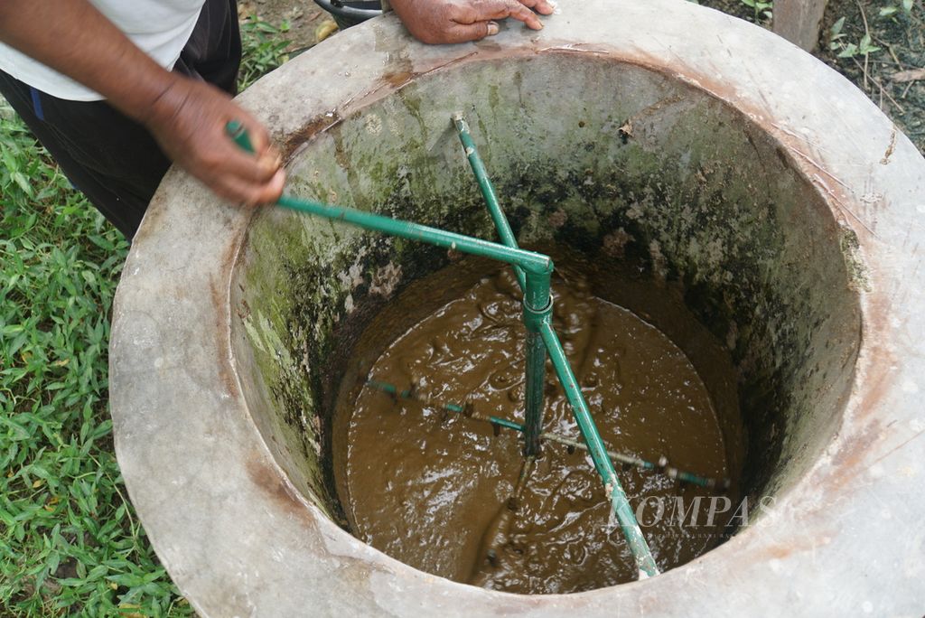Supandi Asmarejo (52) mengaduk campuran kotoran sapi dan air pada tangki pencampur reaktor biogas di rumahnya di Desa Bandungrejo, Boliyohuto, Kabupaten Gorontalo, Provinsi Gorontalo, Senin (29/11/2021).