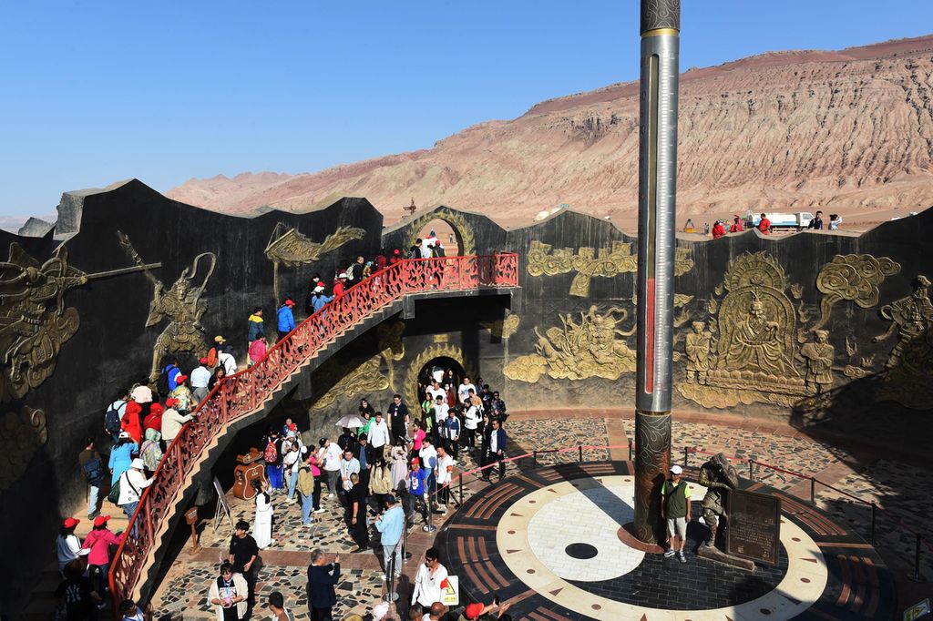 Pengunjung berjalan melewati termometer raksasa di lokasi wisata di Pegunungan Flaming di Turpan di Xinjiang, China, Kamis (5/10/2023). Daerah ini dikenal sebagai salah satu tempat terpanas di China. 