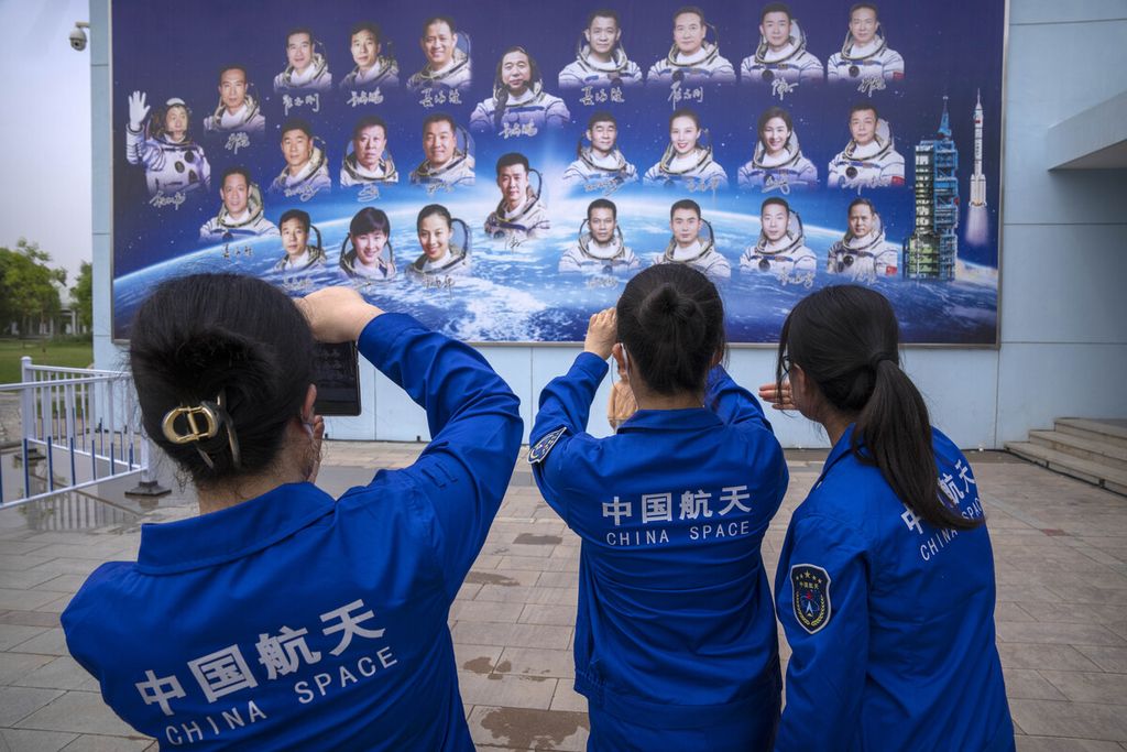 Anggota staf mengambil foto papan reklame yang menggambarkan astronaut China di Pusat Peluncuran Satelit Jiuquan di barat laut China pada Senin (29/5/2023). 