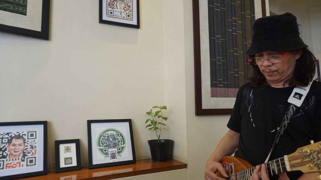 Doddy Mr D Hernanto bermain gitar akustik ukir dengan teknologi QR Art di sela pameran QR Art di Hotel Bisanta Bidakara, Surabaya, Jawa Timur, Senin (8/8/2022). 