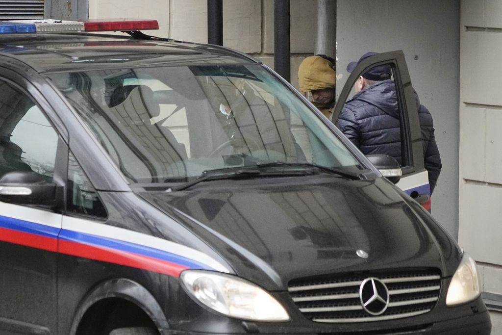 Jurnalis media Amerika Serikat, Evan Gershkovic (tengah, berjaket kuning) dimasukkan ke dalam sebuah van, usai sidang di Pengadilan Moskwa, Kamis (30/3/2023). Gershkovic dituding Dinas Rahasia Rusia FSB melakukan kegiatan spionase untuk pemerintah AS. 