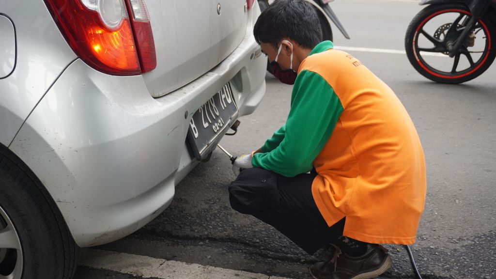 Salah satu mekanik sedang melakukan uji emisi gratis yang diadakan oleh Dinas Lingkungan Hidup DKI Jakarta di Jalan Pemuda, Pulogadung, Jakarta Timur, awal Januari 2021. 