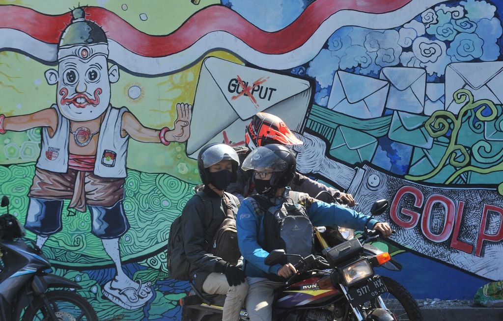 Pengendara melintas di depan mural bertema pilkada serentak di Jalan Raya Ahmad Yani, Kecamatan Waru, Sidoarjo, Jawa Timur, Senin (24/8/2020). 