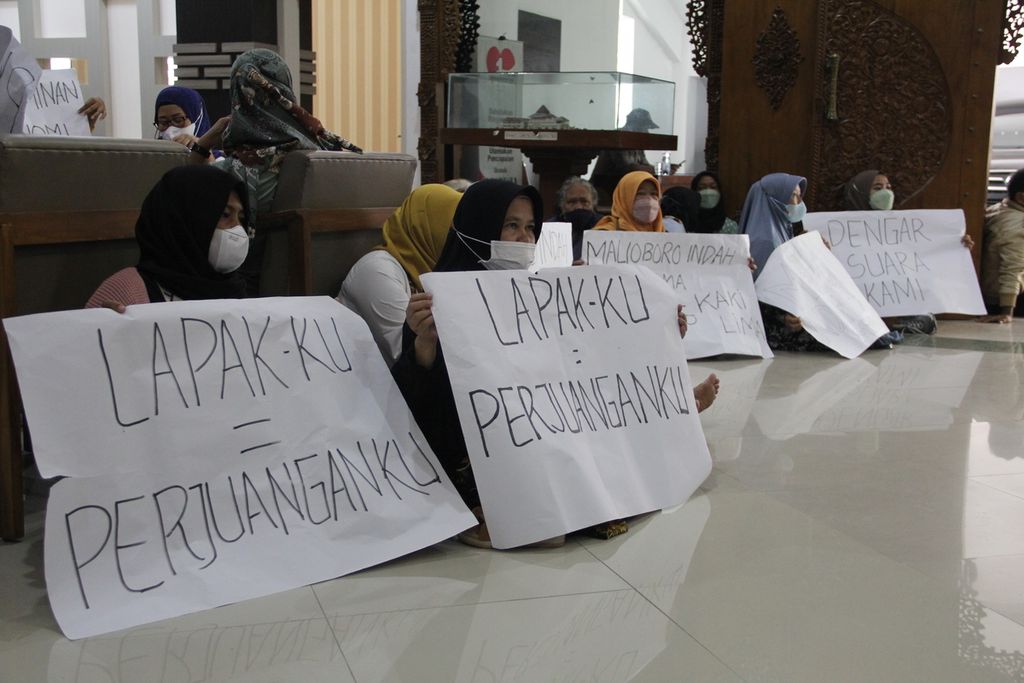 Sejumlah PKL kawasan wisata Malioboro, Kota Yogyakarta, membentangkan poster di Gedung DPRD Kota Yogyakarta, Senin (17/1/2022). Dalam kesempatan itu, mereka mendesak rencana relokasi PKL Malioboro ditunda satu hingga tiga tahun.