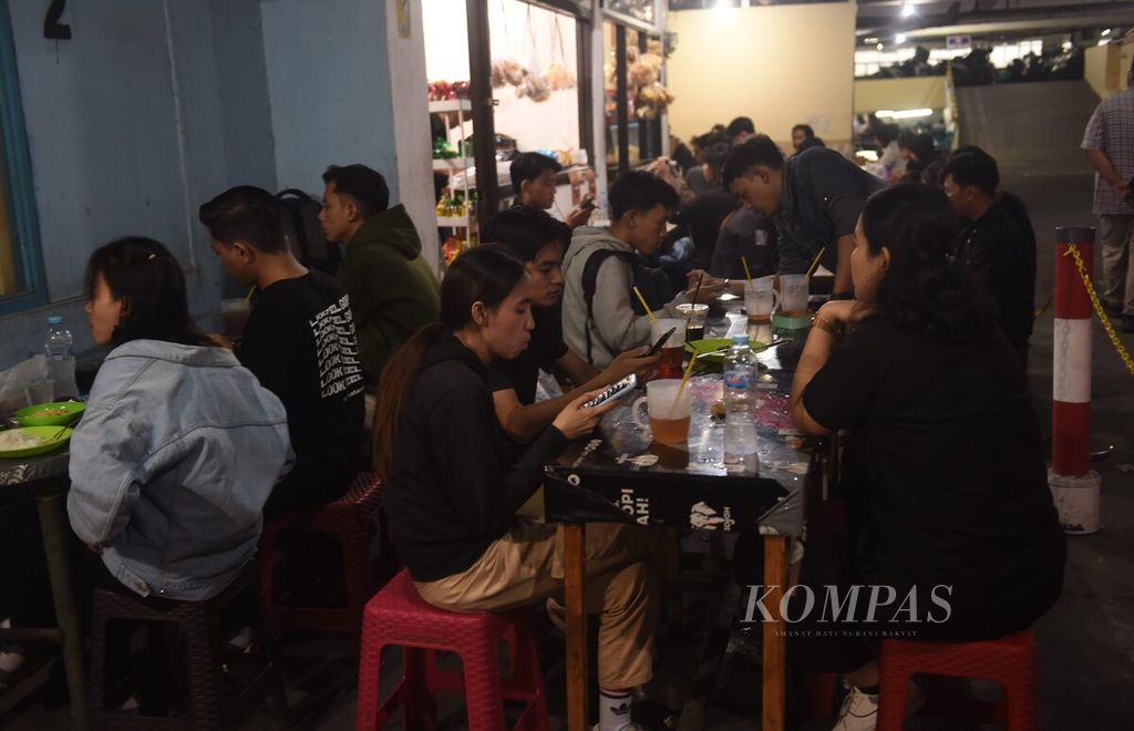 Pekerja berkumpul saat jam pulang kantor di warung makan di sebuah gedung parkir di Jalan Embong Malang, Surabaya, Senin (26/2/2024). Saat ini sebagian besar kelas menengah usia 17-40 tahun kerepotan mengatur pengeluaran. Mereka juga terdampak kenaikan harga bahan pangan.