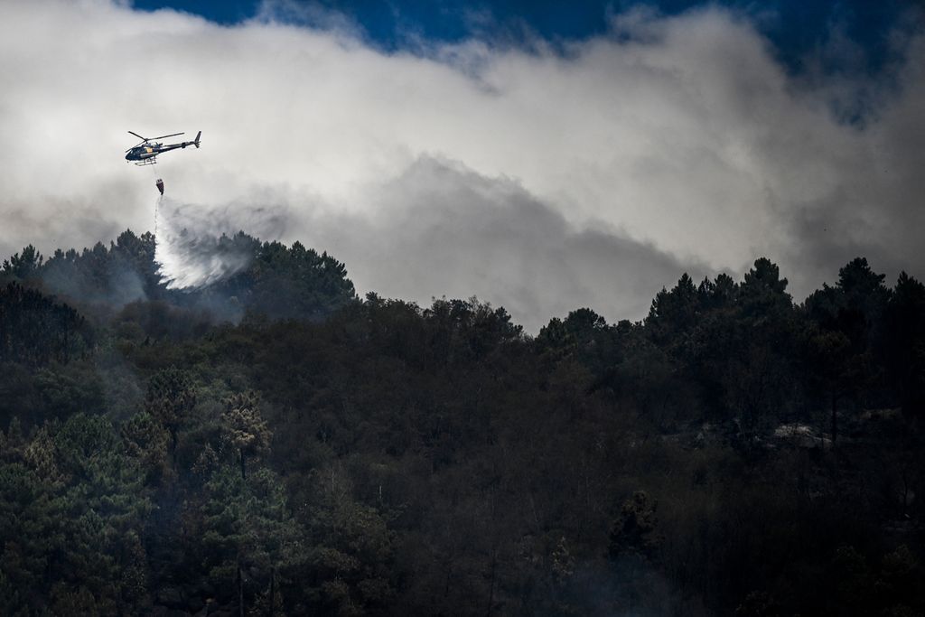 Sebuah helikopter pemadam kebakaran menjatuhkan air saat terjadi kebakaran hutan di Orjais, Covilha, Portugal, 17 Agustus 2022. 