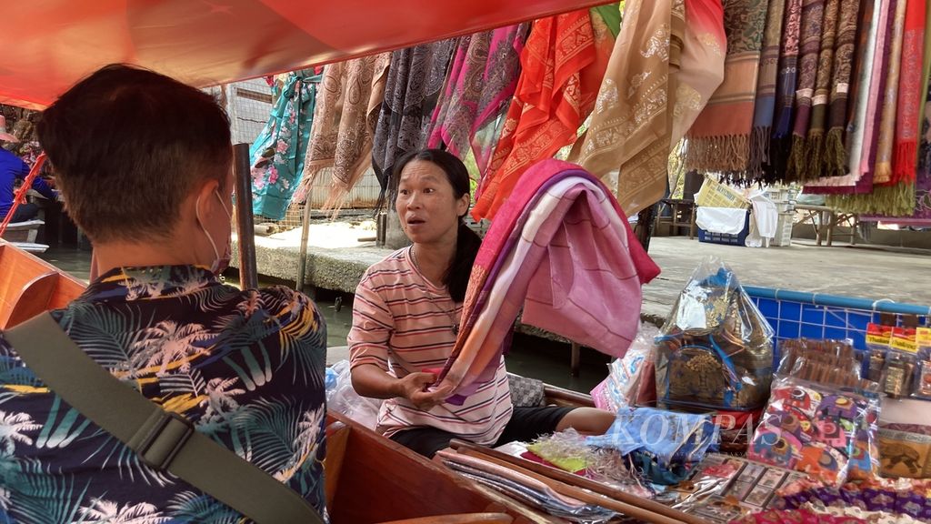 Seorang pedagang menawarkan barang dagangannya di atas perahu menuju Pasar Terapung Damnoen Saduak di Provinsi Ratchaburi, Thailand, Senin (27/3/2023). Praktik perdagangan ini masih berlangsung hingga sekarang dan menjadi salah satu atraksi pariwisata Thailand. 