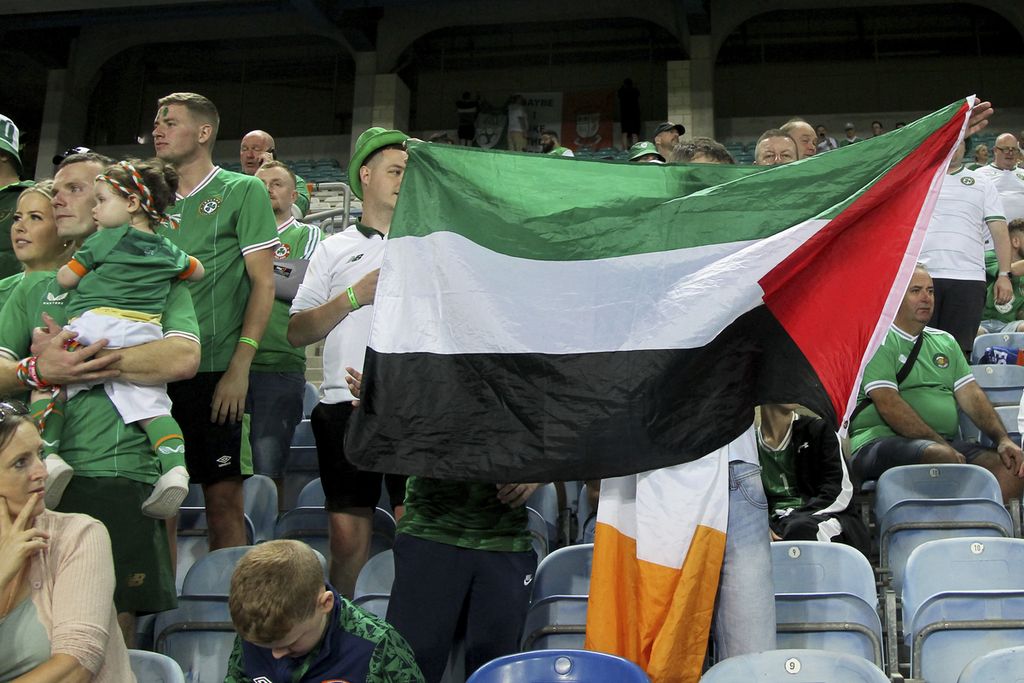 Suporter Irlandia mengibarkan bendera Palestina di tribune penonton saat berlangsung laga kualifikasi Piala Eropa 2024 antara Gibraltar dan Irlandia di Stadion Argarve, di luar Faro, Portugal, 16 Oktober 2023. 