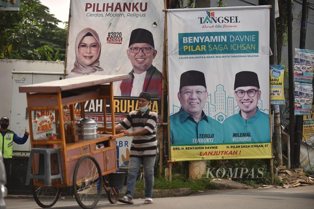 Pengendara melintasi baliho pasangan calon wali kota dan wakil wali kota Tangerang Selatan di kawasan Pondok Aren, Tangerang Selatan, Banten, Kamis (1/10/2020). 