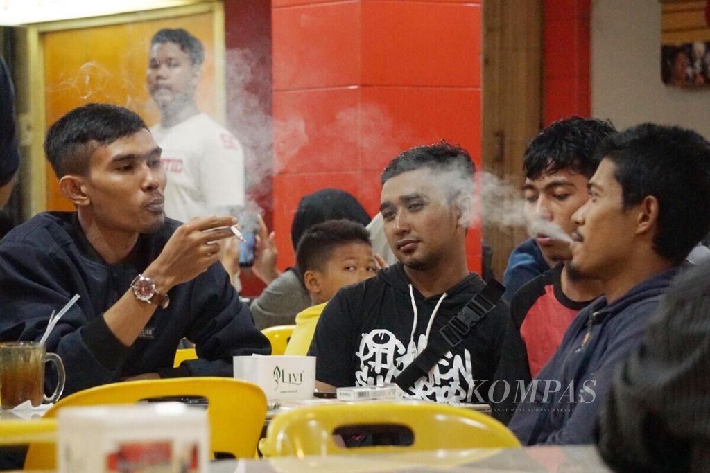 Para pengunjung warung kopi di Banda Aceh, Aceh, sedang merokok, Sabtu (20/7/2019). Merokok pada usia muda semakin meningkatkan risiko kanker. 