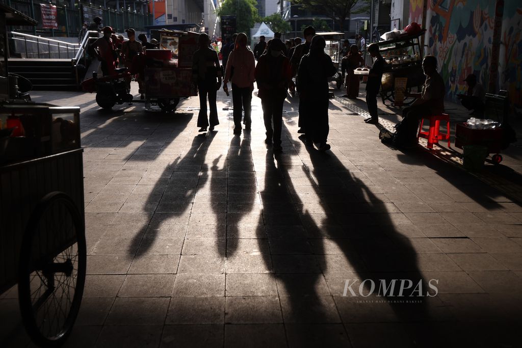 Siluet para pekerja saat berjalan di kawasan Dukuh Atas, Jakarta, Selasa (23/4/2024).
