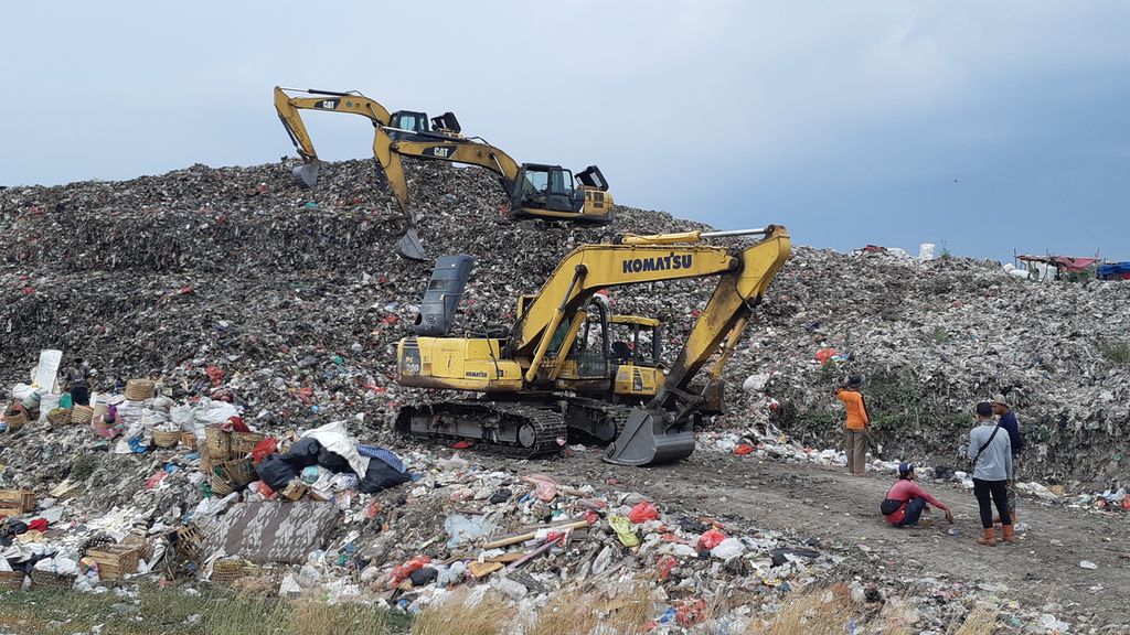 Sejumlah pekerja meratakan gunungan sampah di TPA Jabon, Sidoarjo, Jumat (29/10/2021). Puluhan truk pengangkut sampah rumah tangga antre membongkar muatannya sejak Kamis karena TPA kelebihan kapasitas.