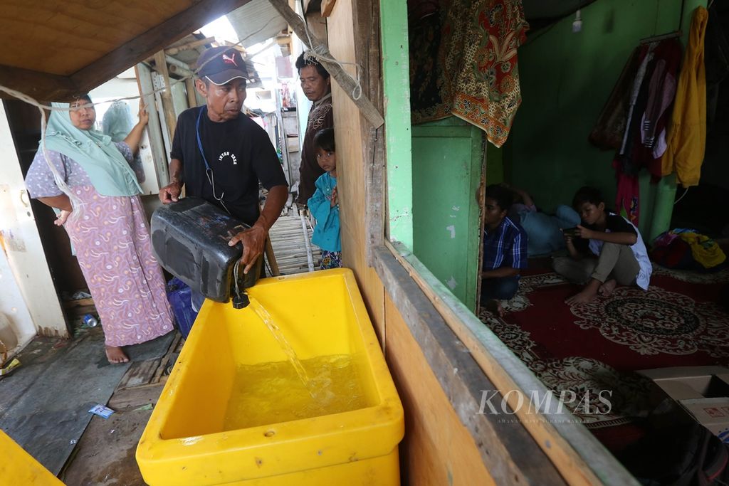 Suparto melayani pembeli air pikulannya di Kali Adem, Penjaringan, Jakarta Utara, Kamis (22/8/2019). 