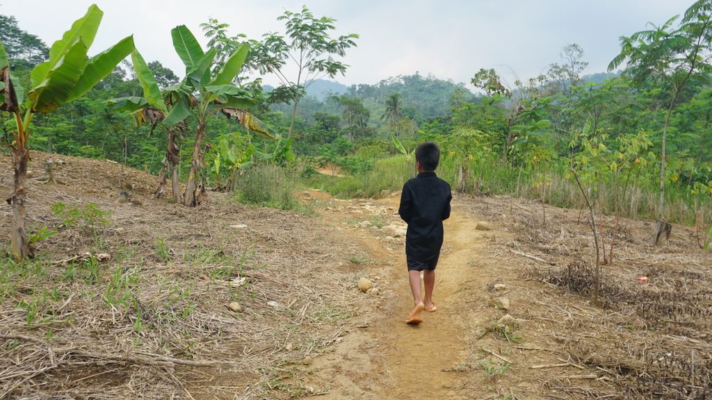 Sardin (11) berjalan tanpa alas kaki menuju wilayah Baduy Dalam di Kabupaten Lebak, Banten, Sabtu (10/6/2023). Tiga tahun lalu, Sardin mengalami lumpuh akibat kecelakaan. Ia akhirnya bisa sembuh setelah mendapatkan perawatan kesehatan yang ditanggung dalam program JKN.