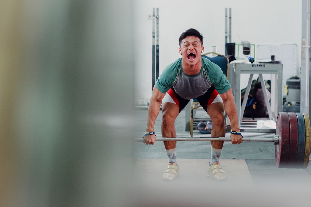 Lifter Indonesia, Rizki Juniansyah, berteriak saat mengangkat beban dalam latihan persiapan Olimpiade Paris 2024 di Mess Kwini, Jakarta, Jumat (24/5/2024). Rizki sangat ekspresif saat mengangkat beban. Baginya, teriakan itu bisa membantu untuk mengeluarkan seluruh energi.