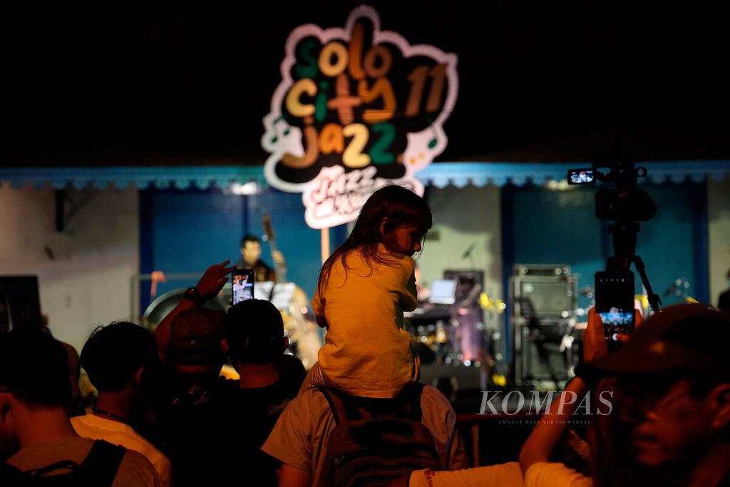Orangtua membawa serta anaknya untuk menonton acara Solo City Jazz di Kori Kamandungan, Kompleks Keraton Surakarta, Kota Surakarta, Jawa Tengah, Jumat (14/10/2022). Pada 14-15 Oktober, pertunjukan musik jazz digelar di Keraton Surakarta dan Pura Mangkunegaran. Agenda tahunan ini menjadi daya tarik wisata bagi Surakarta.