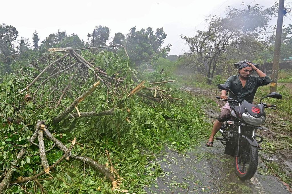 Seorang pengendara sepeda motor melintasi pohon yang tumbang akibat topan Mocha di Teknaf, Bangladesh, Minggu (14/5/2023). 