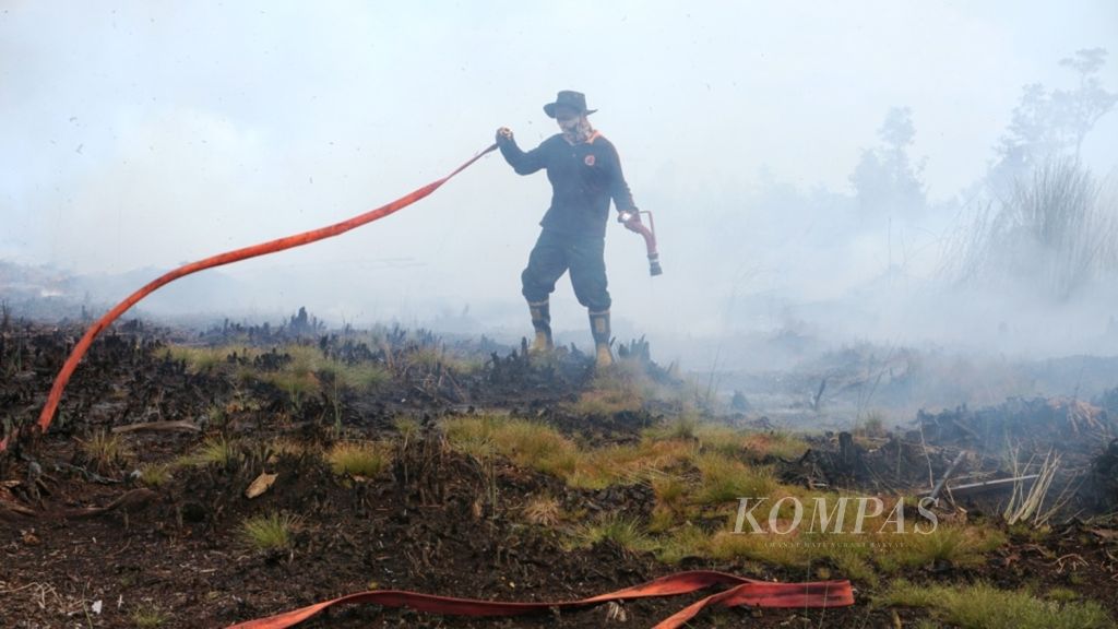 Salah satu anggota tim pemadam kebakaran hutan dan lahan dari Manggala Agni Daerah Operasional Palangkaraya menyiapkan selang untuk memadamkan kebakaran di Petuk Katimpun, Palangkaraya, Kalimantan Tengah, Minggu (19/8/2018). Sampai Senin (20/8/2018), titik panas di Kalteng mencapai 146 titik dan terus meningkat.