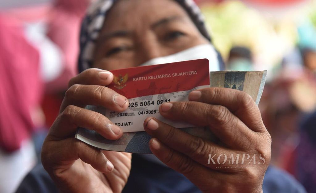 Warga seusai mencairkan bantuan saat penyaluran bantuan Program Keluarga Harapan, Bantuan Pangan Non-Tunai, dan bantuan langsung tunai minyak goreng di Kantor Kecamatan Rungkut, Kota Surabaya, Jawa Timur, Sabtu (16/4/2022). 