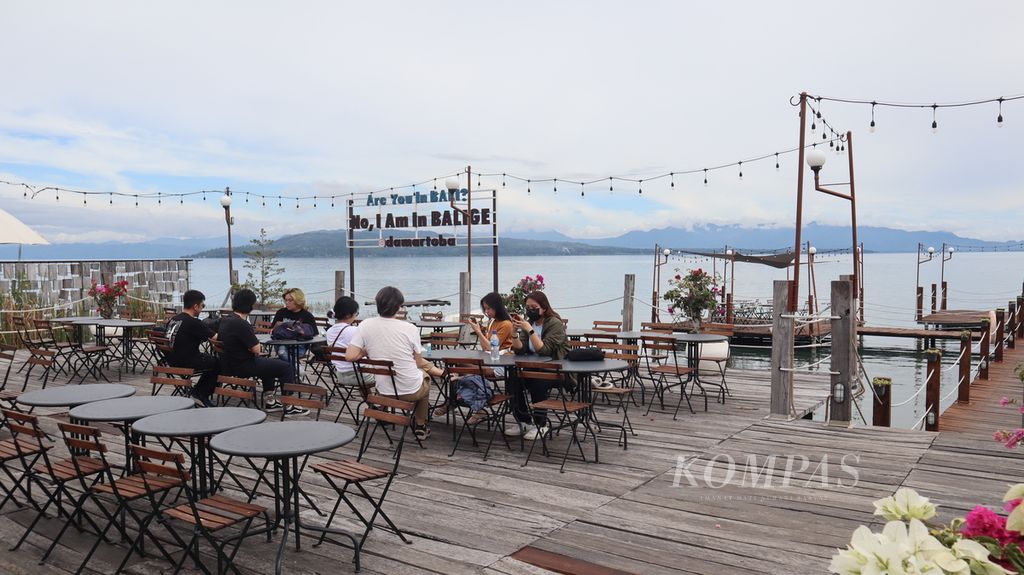 Wisatawan duduk santai di tempat makan luar ruangan Damar Hotel, di Kecamatan Balige, Kabupaten Toba, Sumatera Utara, Kamis (16/11/2023). Pengalaman makan mewah di pinggir Danau Toba menjadi daya jual tempat tersebut.