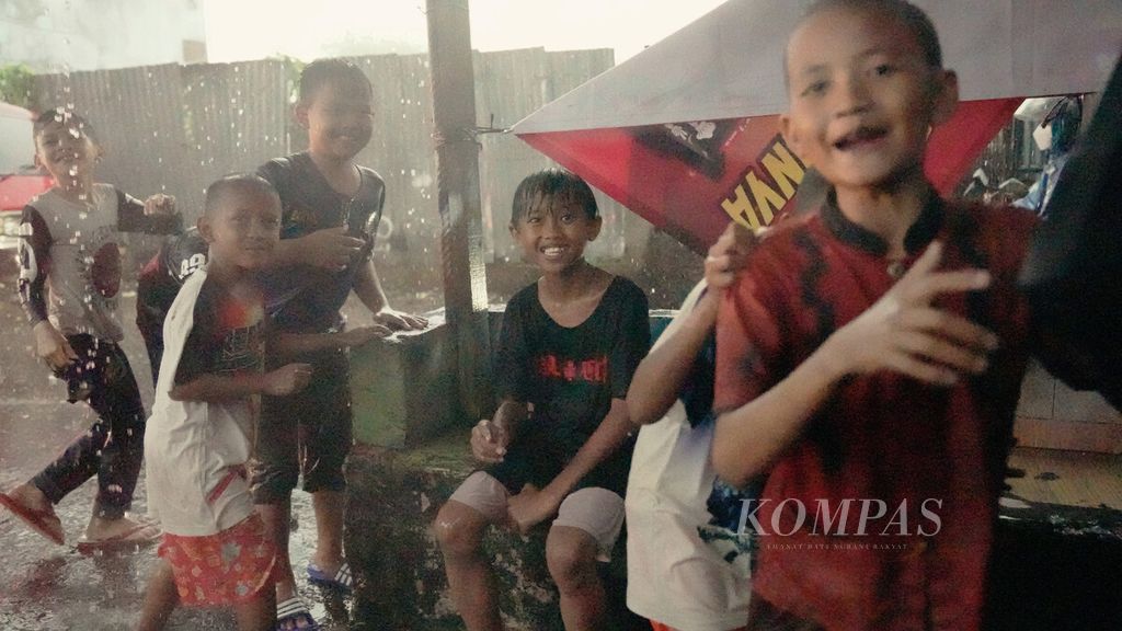 Anak-anak bermain air hujan di Rawa Bunga, Jatinegara, Jakarta Timur, 12 November 2021. 