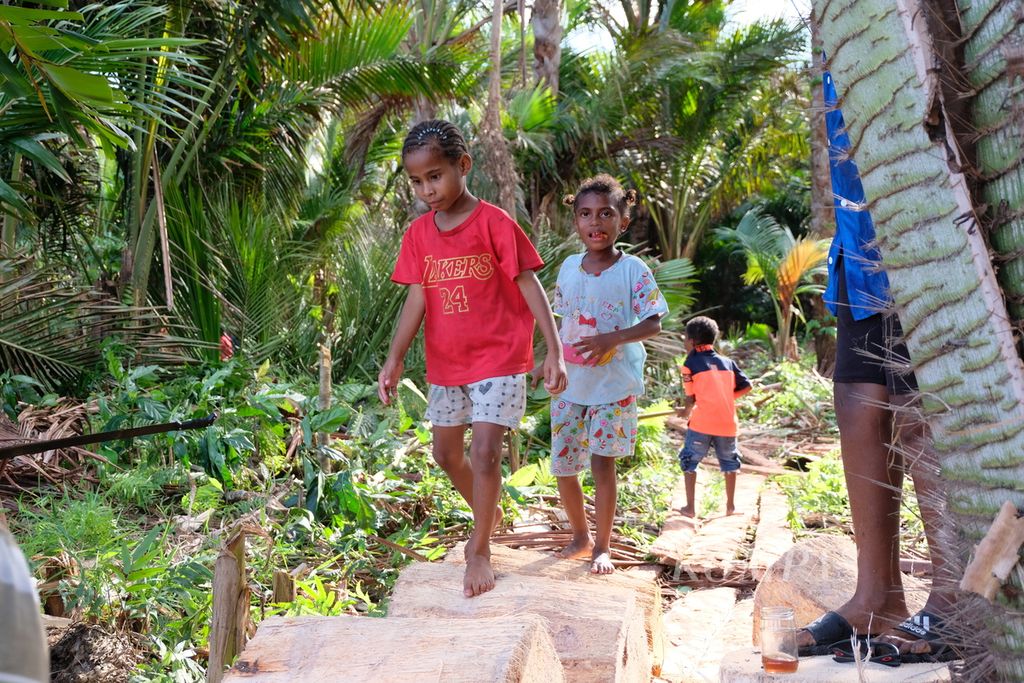 Sejumlah anak melewati batang pohon sagu yang telah dipotong-potong di Kampung Yoboi, Distrik Sentani, Papua, Selasa (29/8/2023). Warga kampung menyebut, sedikitnya ada 30 jenis sagu di hutan yang menjadi daya tarik wisata Kampung Yoboi. 