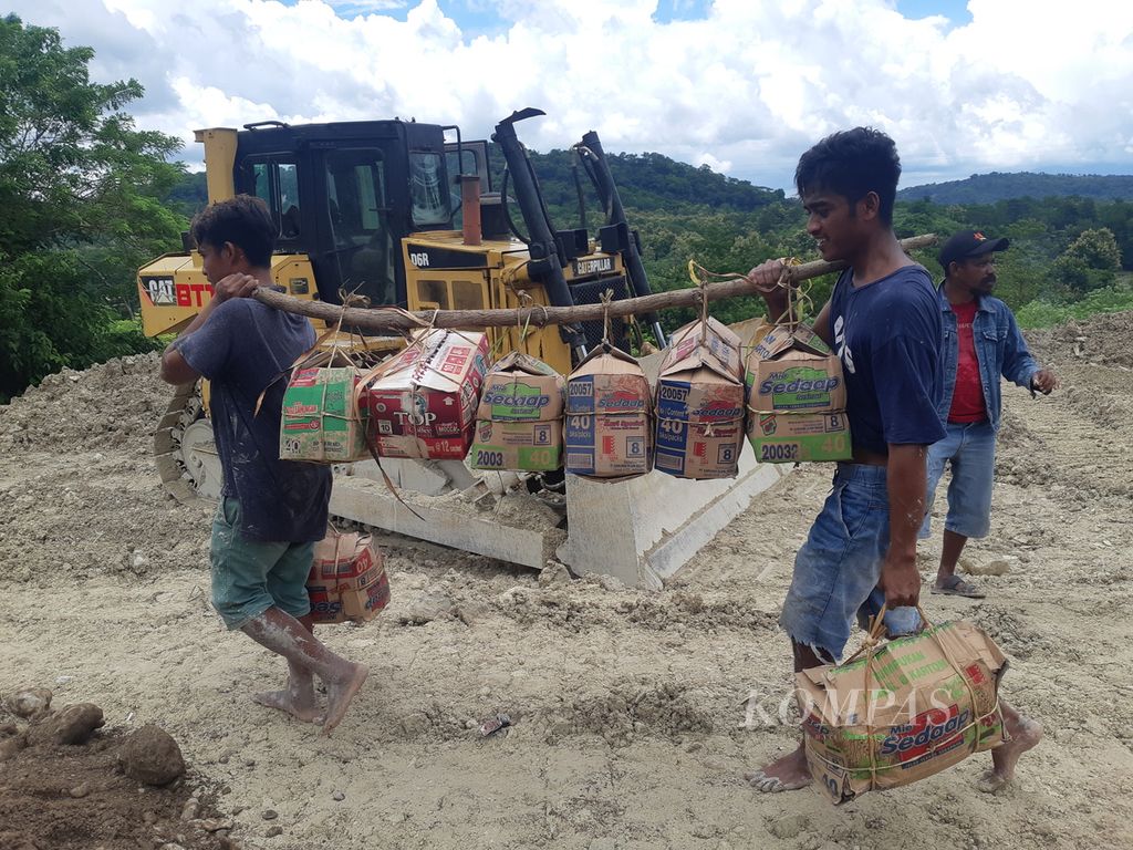Buruh panggul melintasi lokasi longsor di Kelurahan Takari, Kabupaten Kupang, Nusa Tenggara Timur, pada Senin (20/2/2023). Sekali melintas, mereka dibayar Rp 20.000 hingga Rp 50.000.