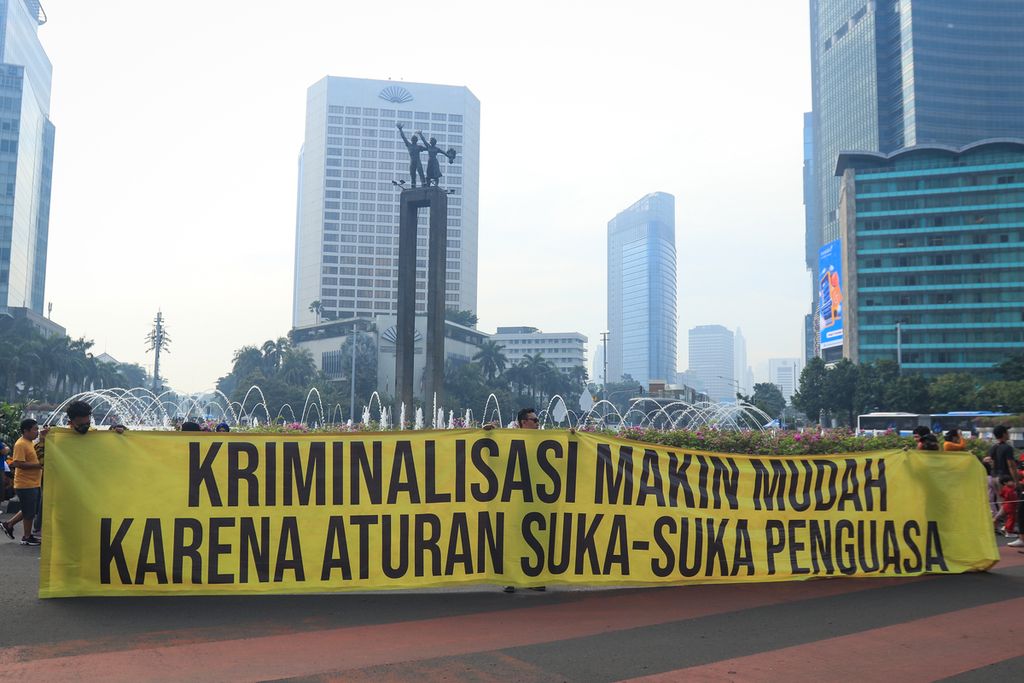 Para peserta aksi membentangkan spanduk penolakan RKUHP di kawasan Bundaran Hotel Indonesia, Jakarta, Minggu (27/11/2022). Aliansi Masyarakat Tolak RKUHP menggelar aksi dengan membentangkan spanduk bertuliskan kalimat kritik pada hari bebas kendaraan bermotor (HBKB). 