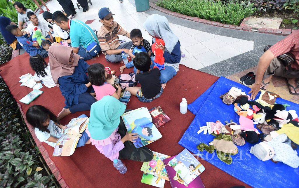 Warga membaca buku dan bermain boneka tangan di pojok Perpustakaan Keliling Kota Surabaya saat hari bebas kendaraan bermotor di Jalan Darmo, Surabaya, Minggu (9/2/2020).