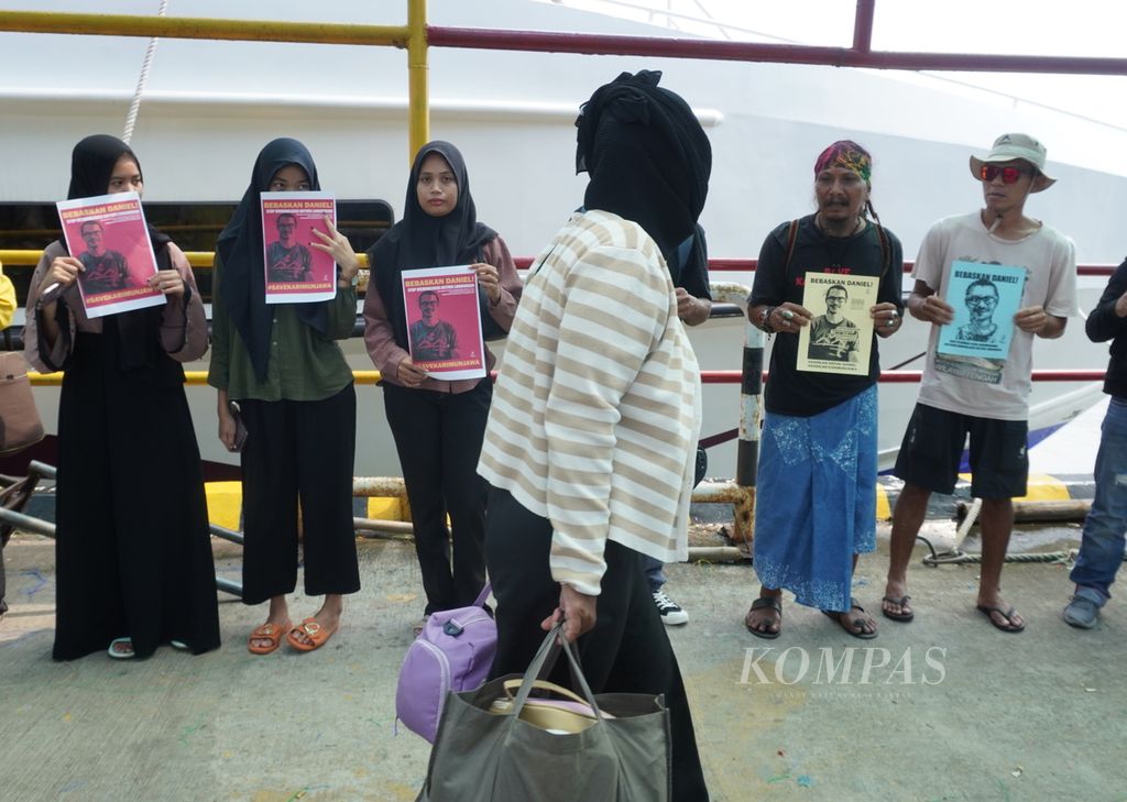 Sejumlah orang yang tergabung dalam gerakan #SaveKarimunjawa bersama dengan warga Karimunjawa membagikan poster berisi tuntutan pembebasan terhadap Daniel Tangkilisan di Pelabuhan Kartini, Jepara, Jawa Tengah, Rabu (3/4/2024). 